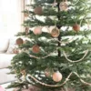 Rustic Reindeer ornament alongside wooden decorative garland and pine cones on fir artificial Christmas tree