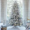 Pre-lit Queen Flock LED Lux Full Artificial Christmas Tree glowing with warm lights in front of a window.