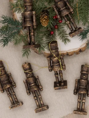 Christmas Jungle six bronze nutcracker glass ornaments arranged on linen near pine branches and berries.