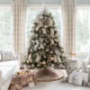 Full view of a Christmas tree draped in Champagne Ribbon next to a white sofa and festive decor.