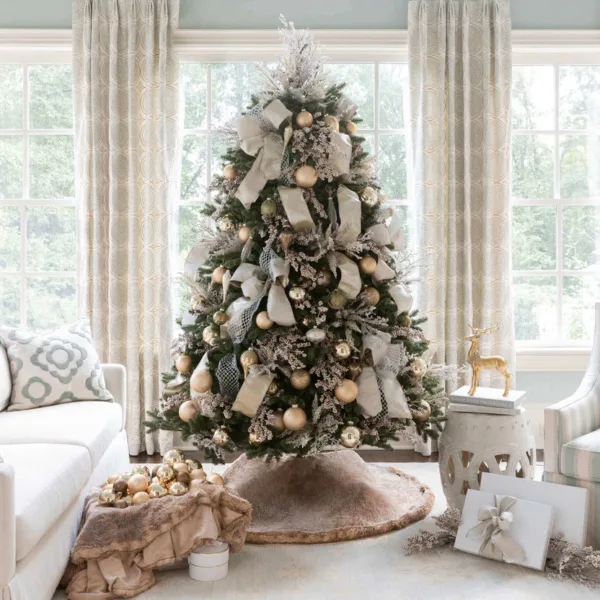 Full view of a Christmas tree draped in Champagne Ribbon next to a white sofa and festive decor.