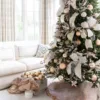 Angle view of a decorated Christmas tree with Champagne Ribbon bows and gold baubles in a bright living room.