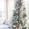 Champagne Ribbon cascading down a flocked Christmas tree decorated with silver, bronze, and icy blue ornaments.
