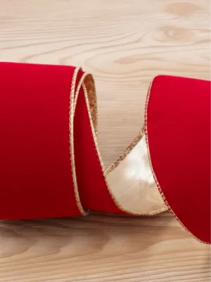 Close-up of coiled Classic Red Ribbon with metallic gold wired edging on a light wooden background.