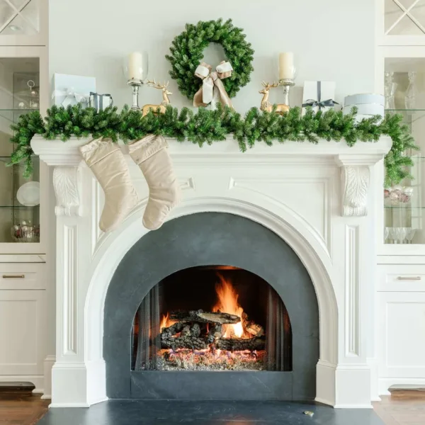 Cypress Spruce Garland layered across a white fireplace mantel decorated with matching wreath, stockings, and gifts.