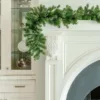 Cypress Spruce Garland with dense evergreen branches draped over the corner of an elegant white fireplace mantel.