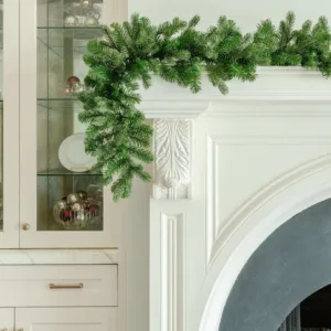 Cypress Spruce Garland with dense evergreen branches draped over the corner of an elegant white fireplace mantel.