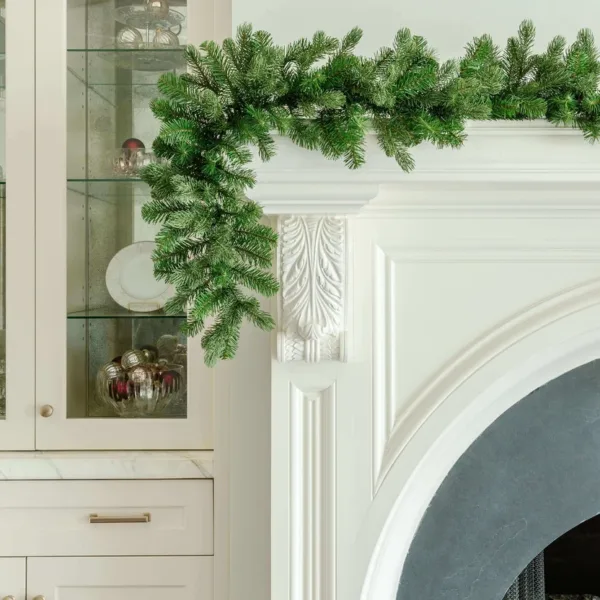 Cypress Spruce Garland with dense evergreen branches draped over the corner of an elegant white fireplace mantel.