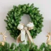 Cypress Spruce Wreath adorned with a taupe and white velvet bow hanging above a garland flanked by gold reindeer.