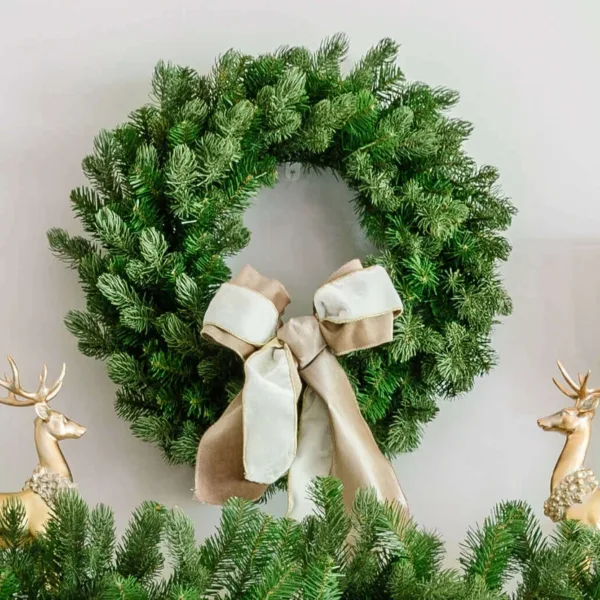 Cypress Spruce Wreath adorned with a taupe and white velvet bow hanging above a garland flanked by gold reindeer.
