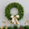 KingDouglasFirWreathUnlit King Douglas Fir Wreath adorned with a gold and white ribbon bow hanging above a mantel flanked by gold reindeer.