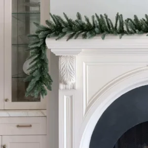 King Noble Fir Garland with blue-green fir branches draped over the edge of a white fireplace mantel.