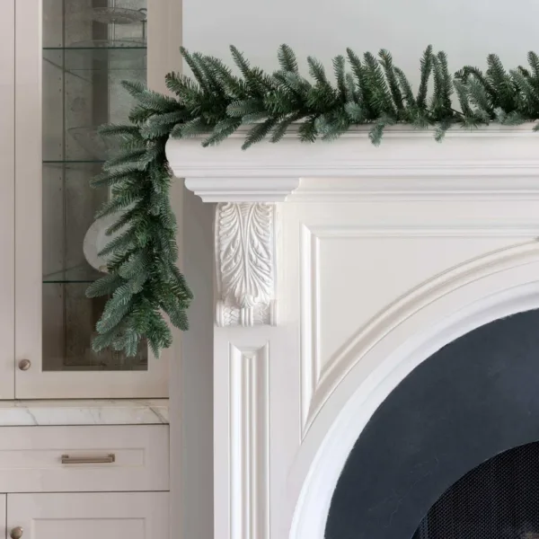 KingNobleGarland1 King Noble Fir Garland with blue-green fir branches draped over the edge of a white fireplace mantel.