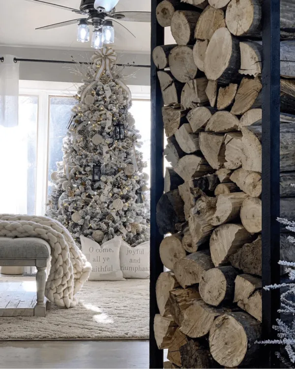 King Flock Full Artificial Christmas Tree decorated with lanterns and cream ribbon framed by a stacked wood rack.