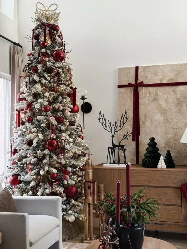 Tall King Flock Slim Artificial Christmas Tree styled with red baubles and plaid ribbon next to modern holiday decor.