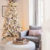 Pre-lit King Flock Full Artificial Christmas Tree with silver ornaments and a starburst topper in a cozy living room nook.