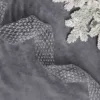 Glittery silver Netted Stretch Ribbon laid out on grey velvet next to frosted pine branches.