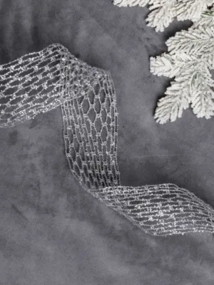 Glittery silver Netted Stretch Ribbon laid out on grey velvet next to frosted pine branches.