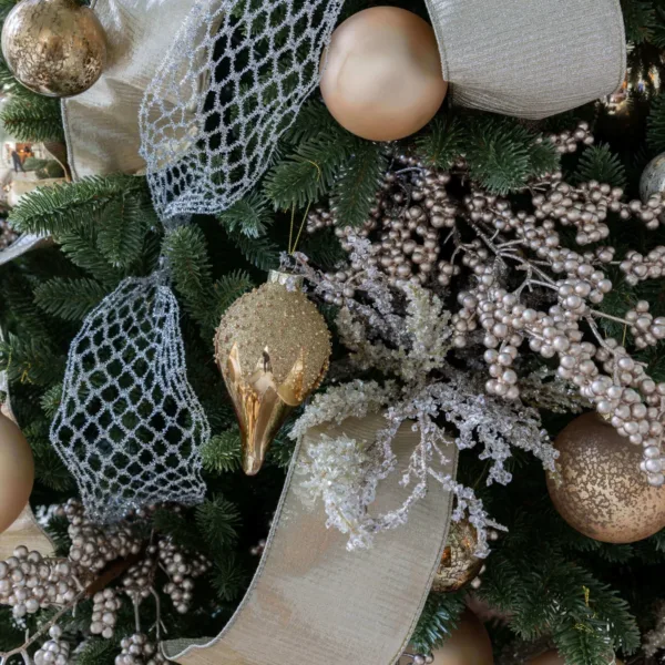 Silver Netted Stretch Ribbon woven through Christmas tree branches alongside gold ornaments and metallic sprays.