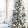 Flocked Christmas tree styled with silver Netted Stretch Ribbon, champagne ribbon, and metallic ornaments.