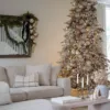 Queen Flock Full Artificial Christmas Tree styled with neutral champagne baubles and ribbon in a bright living room.
