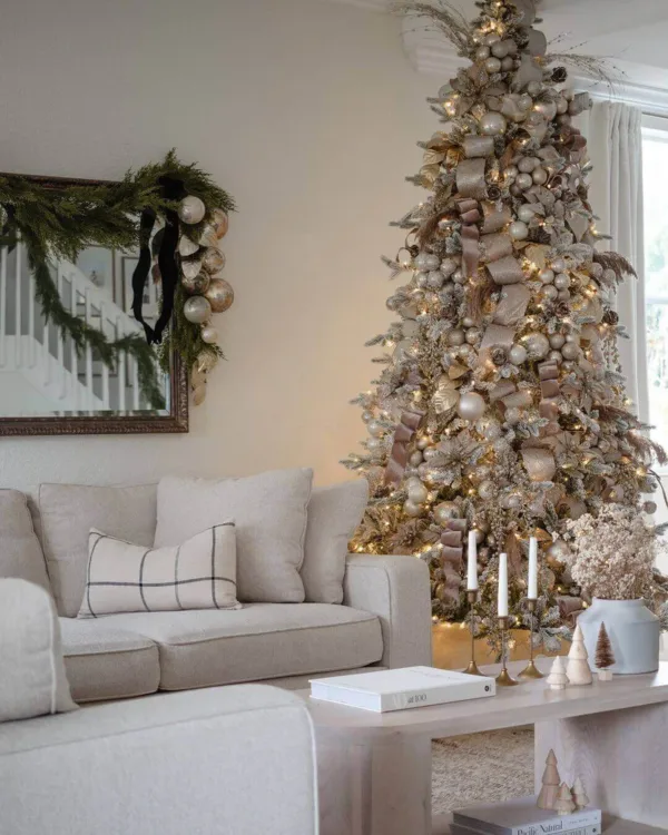 Queen Flock Full Artificial Christmas Tree styled with neutral champagne baubles and ribbon in a bright living room.