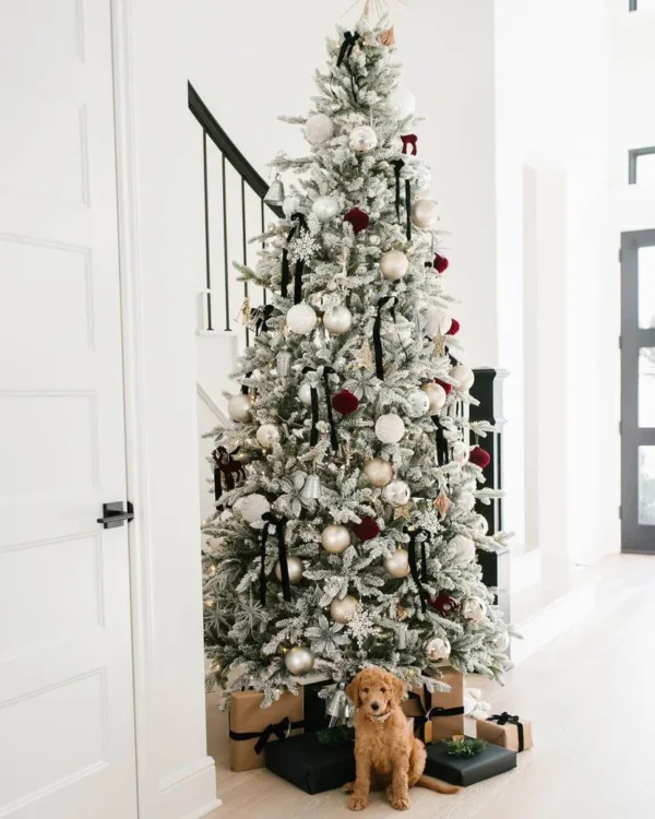 Queen Flock Slim Artificial Christmas Tree styled with black ribbons and gold baubles near a staircase with a puppy sitting below.