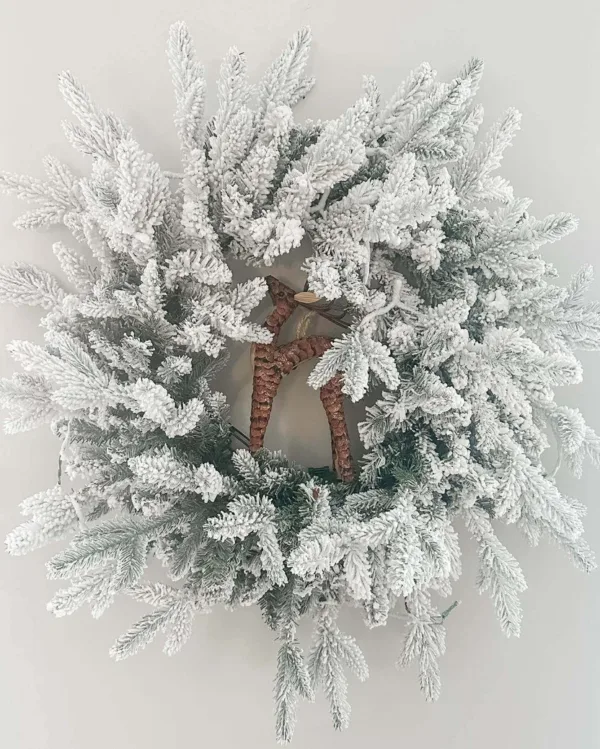 Queen Flock Wreath featuring heavily flocked branches surrounding a small pinecone deer figurine at the center.