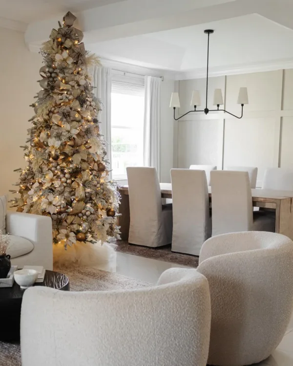 Queen Flock Slim Artificial Christmas Tree lavishly decorated with gold ribbons and champagne ornaments in an open dining room.