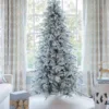 Unlit Queen Flock Slim Artificial Christmas Tree displayed in a sunlit room in front of a window.