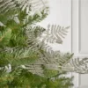 Rosegold Leaf Picks nestled into green pine branches against a white wall background.