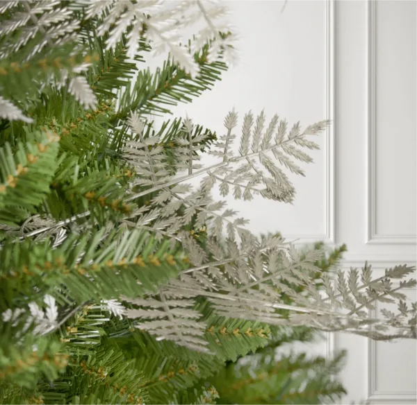 Rosegold Leaf Picks nestled into green pine branches against a white wall background.
