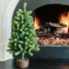 3' Royal Fir Artificial Christmas Tabletop Tree with realistic green needles in a faux wood log stand by a white fireplace hearth.