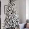Flocked Christmas tree in a living room styled with silver ornaments and silver decorative picks.