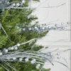 Close-up of glittery Silver Burst Picks with beaded spray branches tucked into evergreen pine branches.
