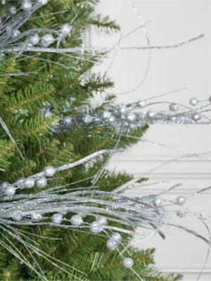 Close-up of glittery Silver Burst Picks with beaded spray branches tucked into evergreen pine branches.