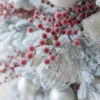 Close-up of frosted red Sugar Berry Picks tucked into a flocked Christmas tree.