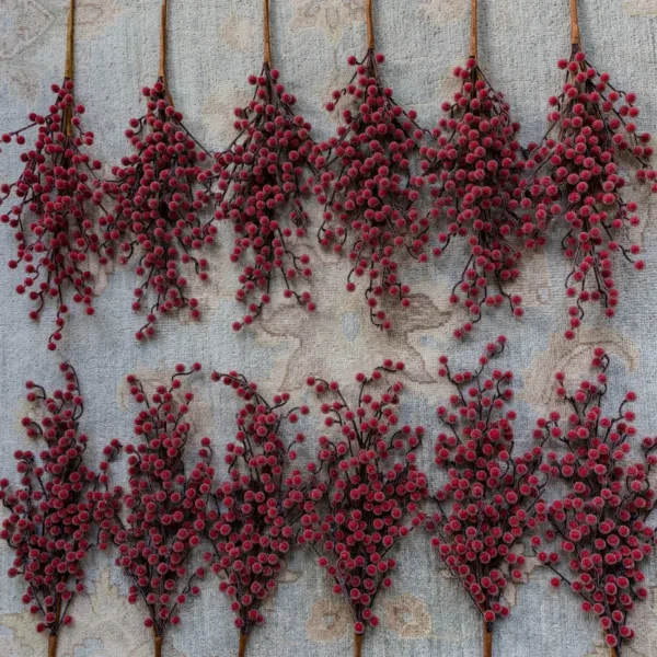 Multiple red frosted Sugar Berry Picks arranged on a light-colored carpet.
