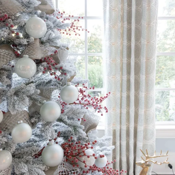 Flocked Christmas tree decorated with red Sugar Berry Picks, white ornaments, and silver ribbon.