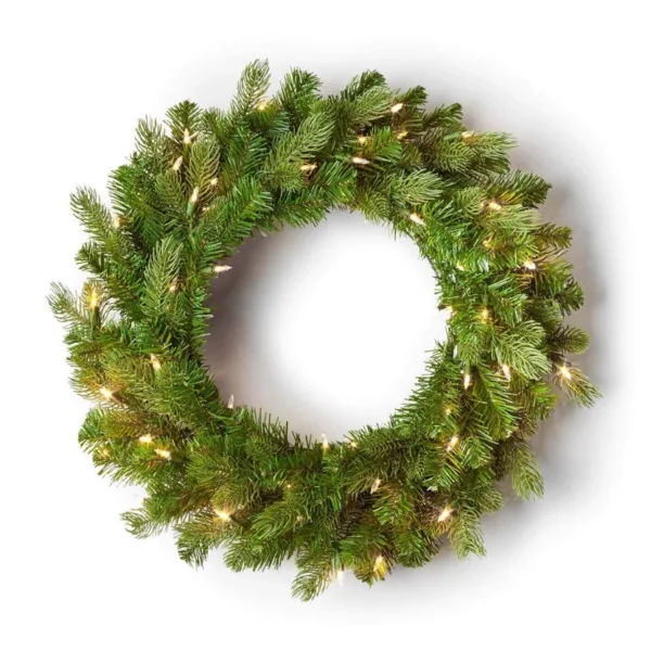 Pre-lit Cypress Spruce Wreath with full green foliage illuminated by warm mini lights on a white background.