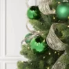 Gold Mesh Ribbon draped through Christmas tree branches alongside green glass ornaments.