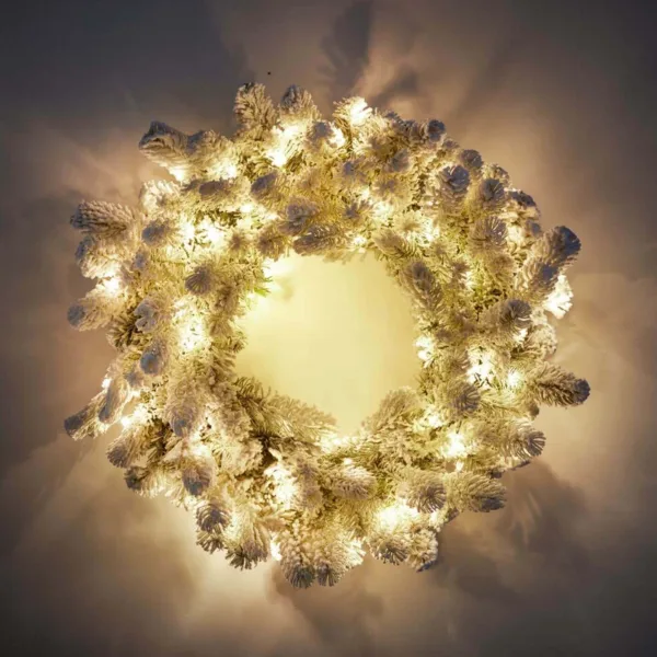 king-flock-prelit-wreath Warmly illuminated pre-lit King Flock Wreath mounted on a dark wall above a vintage "Live Simply" wood sign.