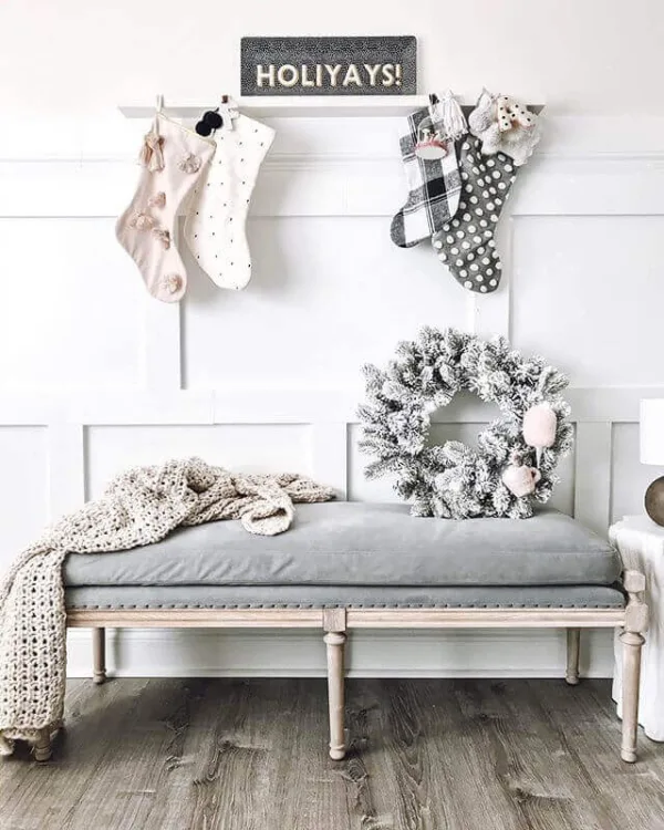 king-flock-wreath-1 King Flock Wreath resting on an upholstered entryway bench below hanging Christmas stockings.