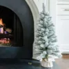 3' King Flock Artificial Christmas Tabletop Tree wrapped in burlap set beside a glowing white fireplace.