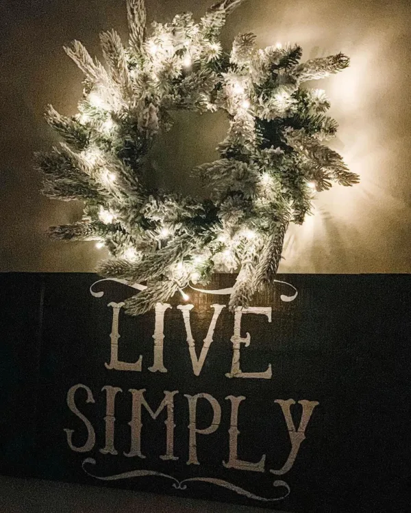 kingflockLitwreath Pre-lit King Flock Wreath glowing directly above a rustic dark wood decorative wall sign.