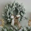 kingflockwreath King Flock Wreath adorned with a taupe and cream velvet bow hanging above a mantel with golden reindeer figurines.