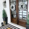 kingflockwreath2 Pair of matching snow-flocked King Flock Wreaths hanging on dark wood glass front doors.