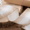 Close-up of white ribbon with gold glittery gradient edges coiled on a wood slice.