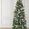 Full view of a pre-lit Christmas tree styled with White Glitter Ribbon loops and silver metallic ornaments.